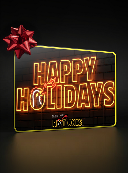 Neon sign with 'Happy Holidays' and a red bow on a dark background